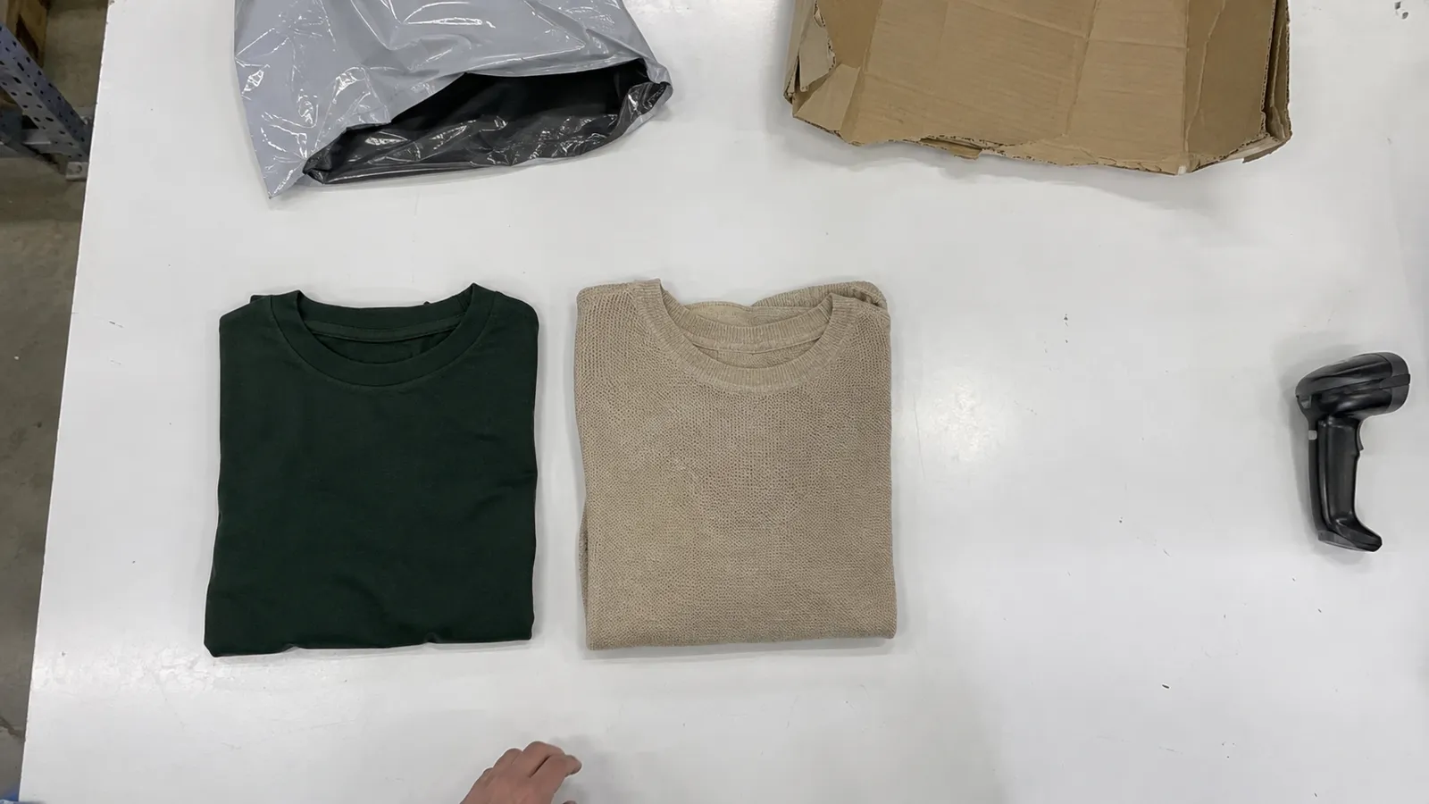 Overhead bench-camera view of an opened parcel with two garments laid out