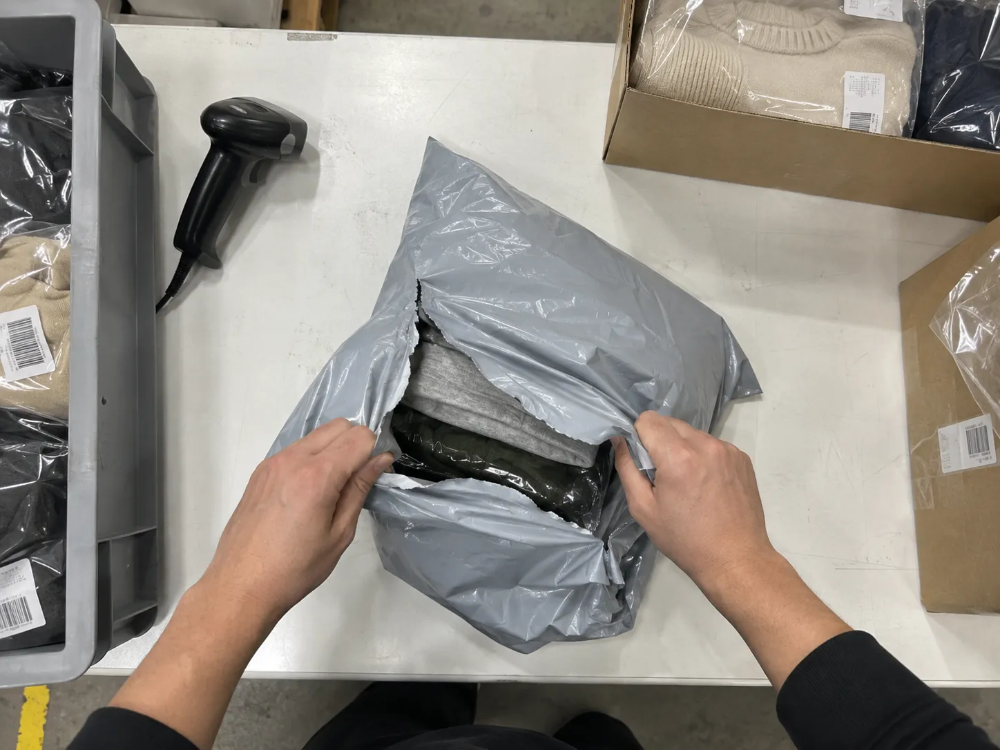 Overhead view of hands opening a returns poly bag on a bench